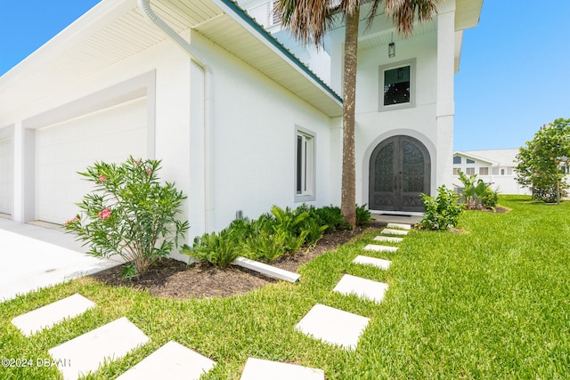 exterior space with a garage, a yard, and french doors