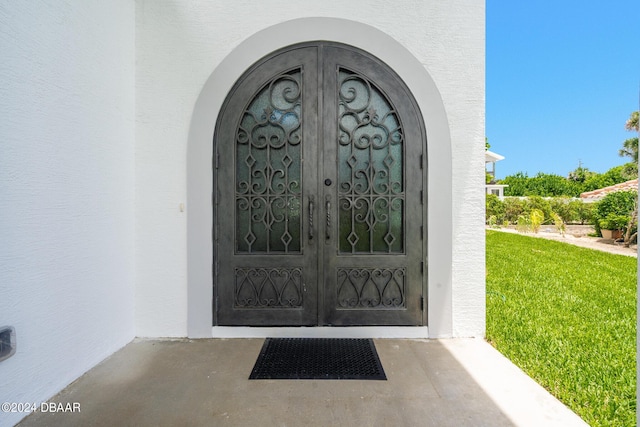 4727 Riverglen Blvd, Ponce Inlet, FL 32127 - view of exterior entry featuring french doors, stucco siding, and a lawn