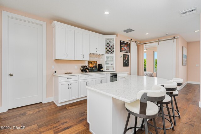 4727 Riverglen Blvd, Ponce Inlet, FL 32127 - kitchen featuring a barn door, a breakfast bar, dark wood-style floors, white cabinetry, and recessed lighting