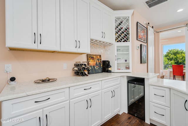 kitchen with wine cooler, dark hardwood / wood-style floors, light stone countertops, and white cabinets