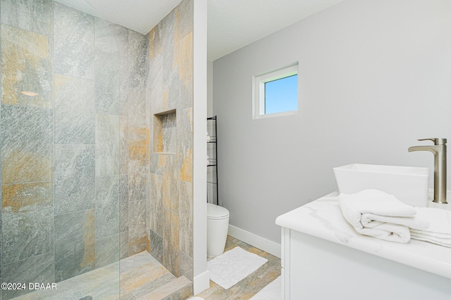 bathroom with vanity, toilet, and a tile shower