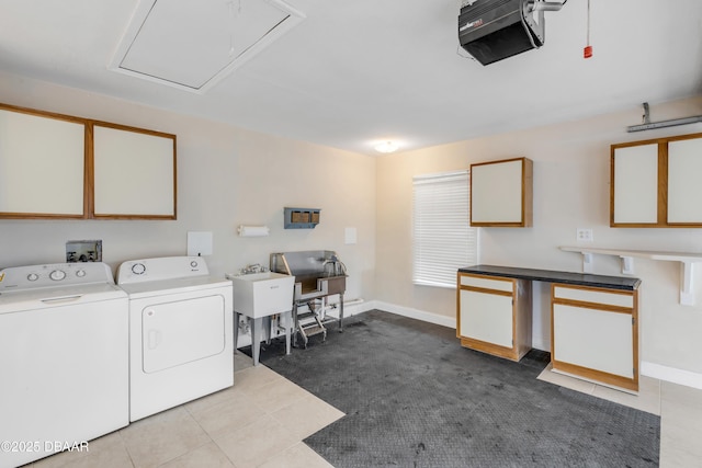 laundry area with light tile patterned floors, sink, washing machine and clothes dryer, and cabinets