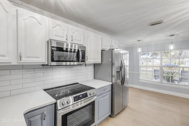 kitchen featuring stainless steel appliances, tasteful backsplash, ornamental molding, pendant lighting, and white cabinets