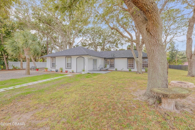 single story home featuring a front yard, a fire pit, and a patio