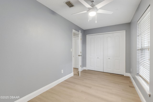 unfurnished bedroom with ceiling fan, a closet, and light wood-type flooring