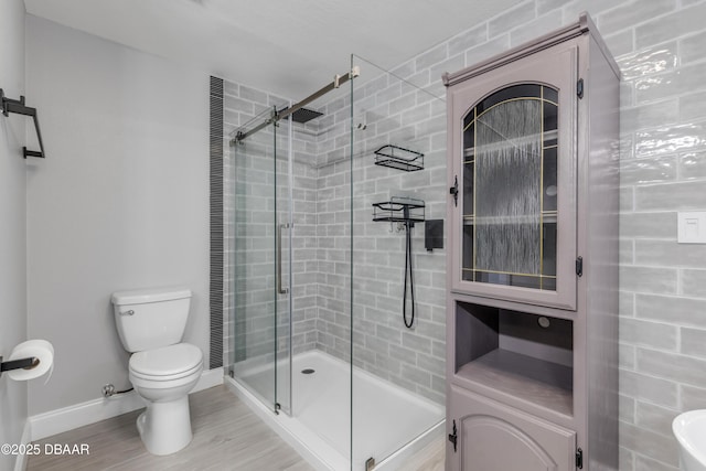 bathroom with wood-type flooring, toilet, and a shower with door