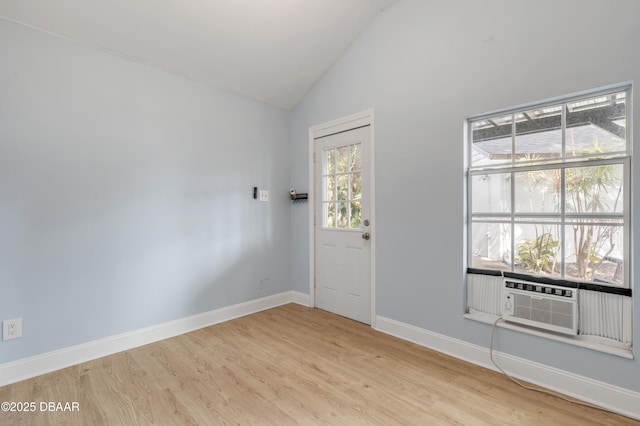 unfurnished room with cooling unit, light wood-type flooring, and vaulted ceiling