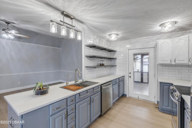 kitchen featuring ceiling fan, kitchen peninsula, sink, white cabinetry, and appliances with stainless steel finishes