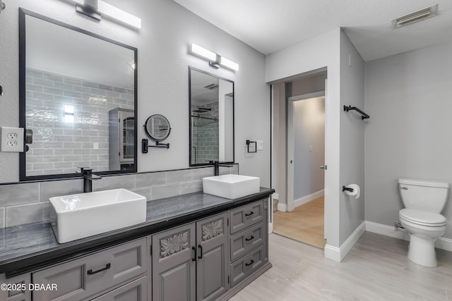 bathroom featuring toilet, tasteful backsplash, wood-type flooring, walk in shower, and vanity