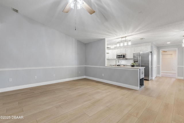 kitchen with backsplash, kitchen peninsula, sink, white cabinetry, and appliances with stainless steel finishes