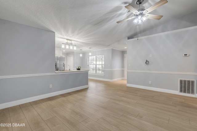 unfurnished living room with light hardwood / wood-style floors, ceiling fan, a textured ceiling, vaulted ceiling, and sink