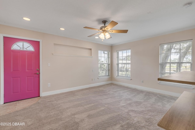 carpeted entrance foyer with ceiling fan and crown molding