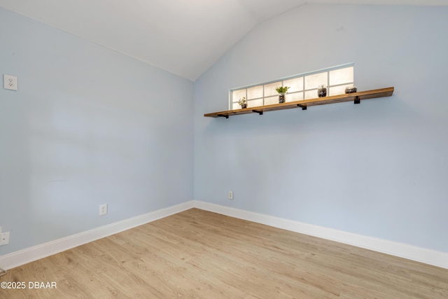 empty room featuring vaulted ceiling and light wood-type flooring