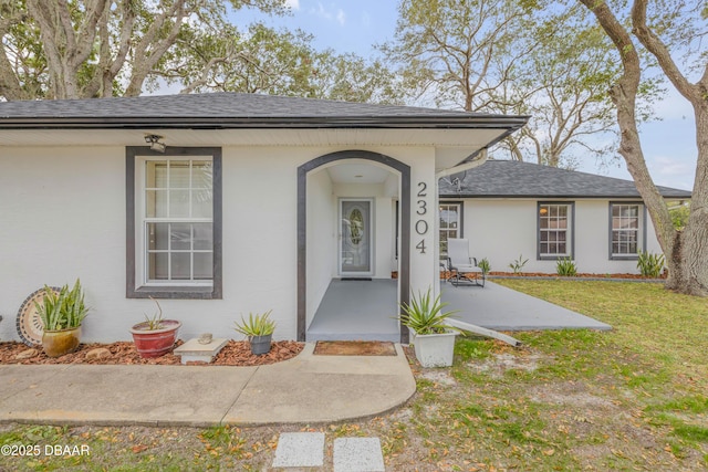 property entrance featuring a lawn and a patio