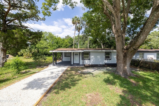 619 Aberdeen St, Daytona Beach, FL 32114 - view of front facade with gravel driveway, an attached carport, and view of wooded area