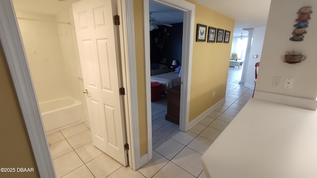 corridor featuring light tile patterned flooring and baseboards