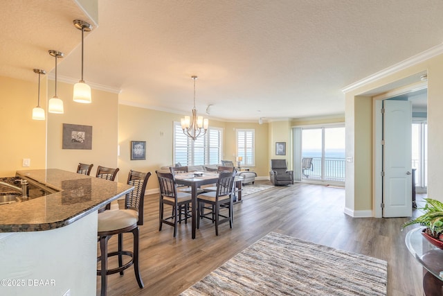 dining room featuring an inviting chandelier, ornamental molding, dark hardwood / wood-style floors, and a textured ceiling