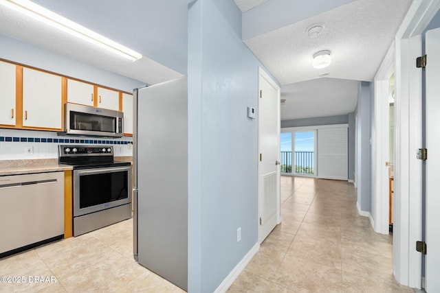 kitchen with baseboards, decorative backsplash, appliances with stainless steel finishes, light countertops, and a textured ceiling