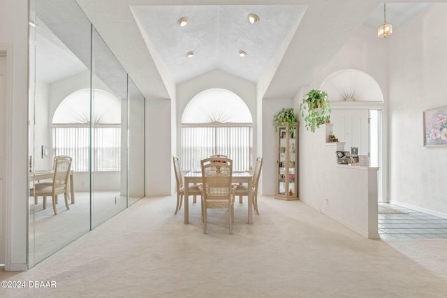 carpeted dining area with high vaulted ceiling