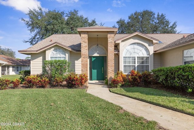 74 Kingsley Ln, Ormond Beach, FL 32174 - view of front of home with a front yard, a shingled roof, and stucco siding