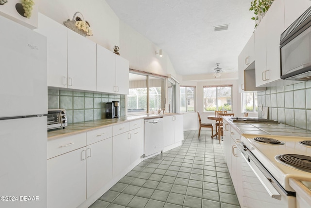 kitchen featuring tasteful backsplash, tile patterned floors, white cabinetry, white appliances, and ceiling fan