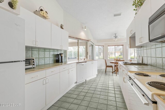 74 Kingsley Ln, Ormond Beach, FL 32174 - kitchen with white appliances, ceiling fan, lofted ceiling, decorative backsplash, and light countertops