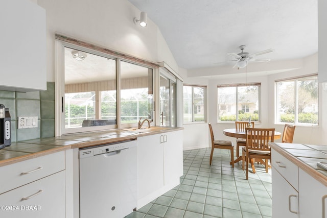 kitchen with white dishwasher, tile countertops, white cabinets, and plenty of natural light