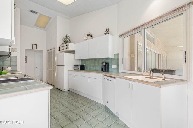 kitchen with white cabinets, sink, white appliances, and light tile patterned floors