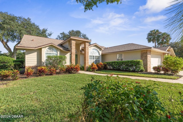 74 Kingsley Ln, Ormond Beach, FL 32174 - view of front of home with a front lawn, an attached garage, a shingled roof, brick siding, and driveway