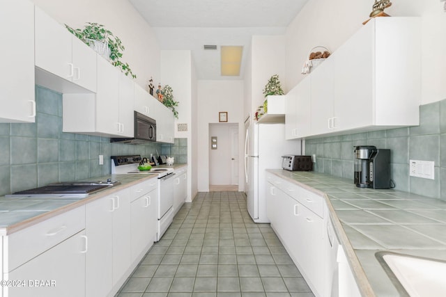 kitchen with tile countertops, white range with electric cooktop, white cabinets, and backsplash