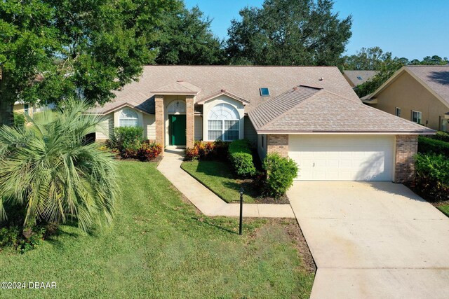 74 Kingsley Ln, Ormond Beach, FL 32174 - single story home featuring brick siding, an attached garage, driveway, a front yard, and roof with shingles