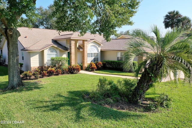 74 Kingsley Ln, Ormond Beach, FL 32174 - view of front of house with roof with shingles, a front yard, and stone siding