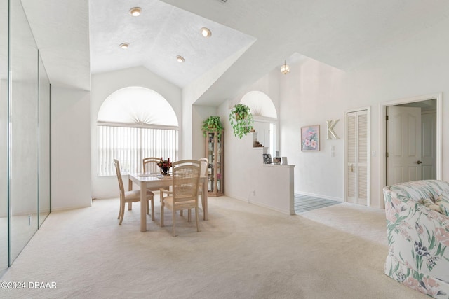 dining area featuring light carpet and high vaulted ceiling