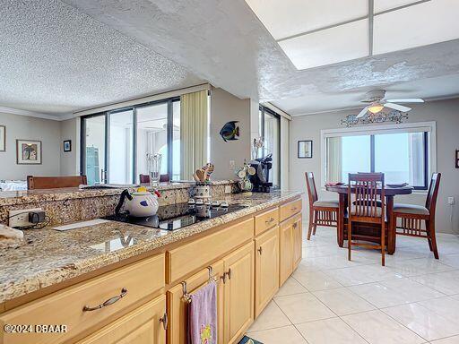 kitchen featuring black electric cooktop, light brown cabinetry, a textured ceiling, and light tile patterned flooring