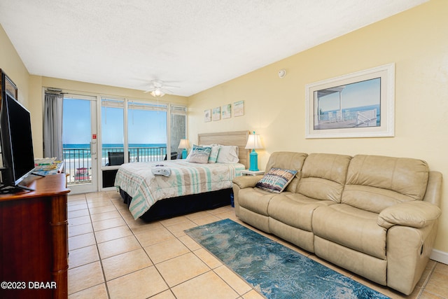 bedroom with a water view, ceiling fan, access to exterior, a textured ceiling, and light tile patterned floors