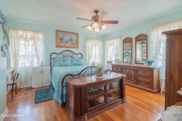 bedroom with ceiling fan, multiple windows, and light hardwood / wood-style flooring