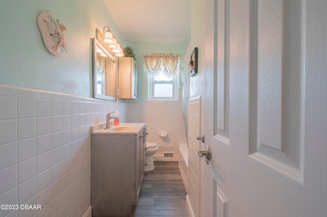 bathroom with toilet, vanity, tile walls, and wood-type flooring