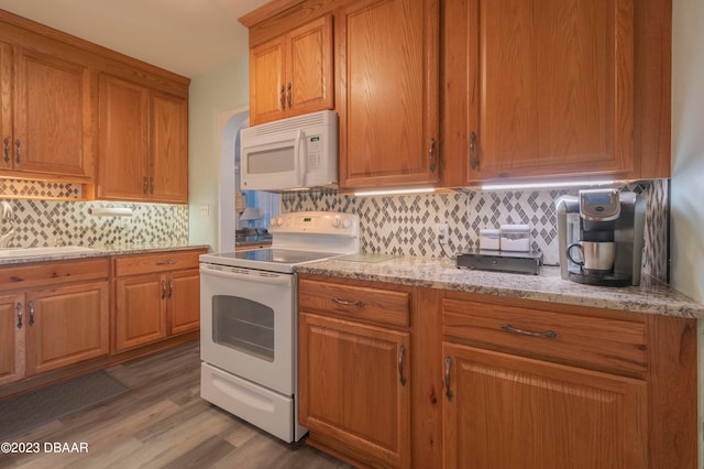 kitchen featuring white appliances, wood-type flooring, sink, and decorative backsplash