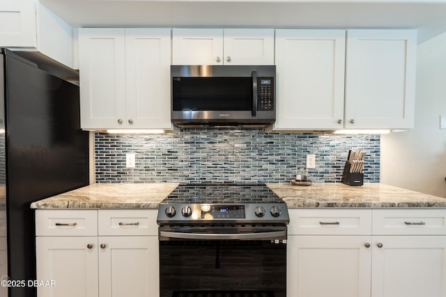 kitchen with electric stove, white cabinetry, black fridge, and light stone counters