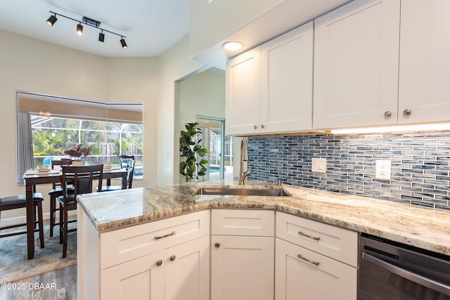 kitchen featuring dishwasher, sink, white cabinets, and light stone counters