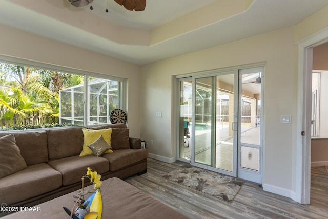 living room featuring hardwood / wood-style flooring, ceiling fan, and a raised ceiling