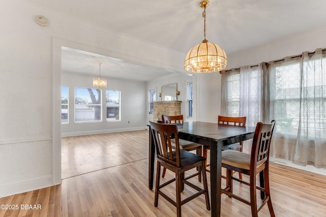 dining room with ornamental molding, light wood-type flooring, and an inviting chandelier