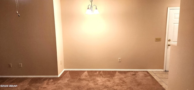 carpeted empty room featuring an inviting chandelier