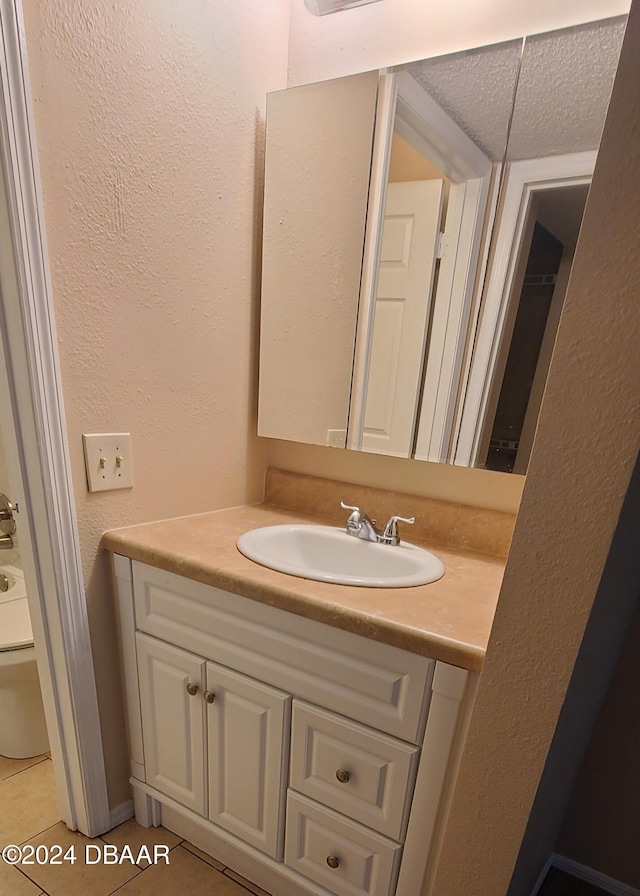 bathroom with tile patterned flooring, vanity, toilet, and a textured ceiling