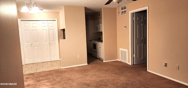 unfurnished bedroom with dark colored carpet, a textured ceiling, ceiling fan with notable chandelier, and a closet