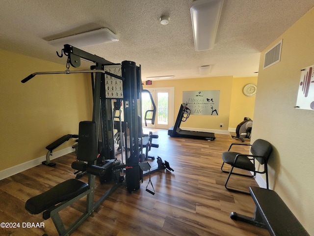 workout room with hardwood / wood-style floors and a textured ceiling