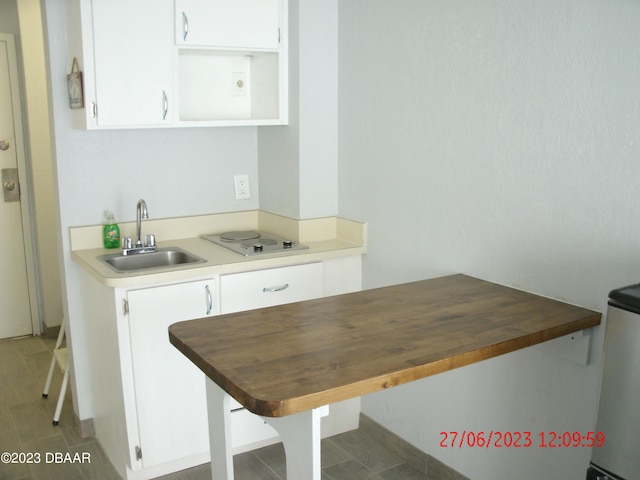 kitchen with white cooktop, white cabinetry, and sink