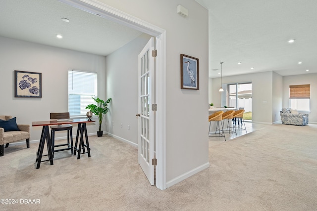 hall featuring light colored carpet, a textured ceiling, and french doors