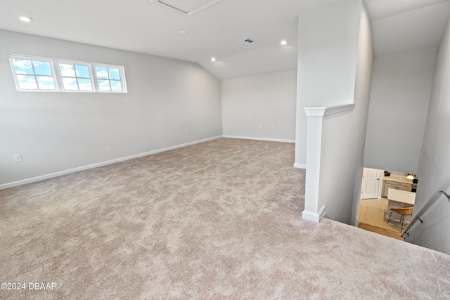 spare room featuring light colored carpet and lofted ceiling