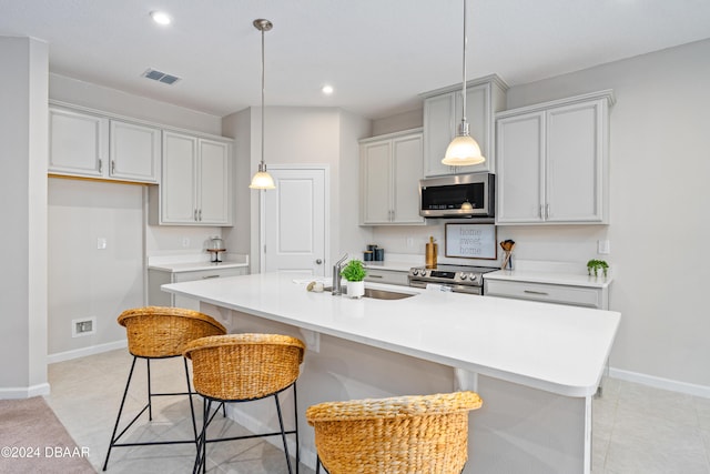 kitchen with a kitchen breakfast bar, a center island with sink, stainless steel appliances, and sink